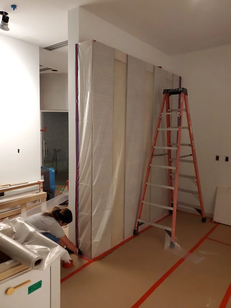 Plastic sheeting and taped seams separate a work area from the rest of a building during containment.