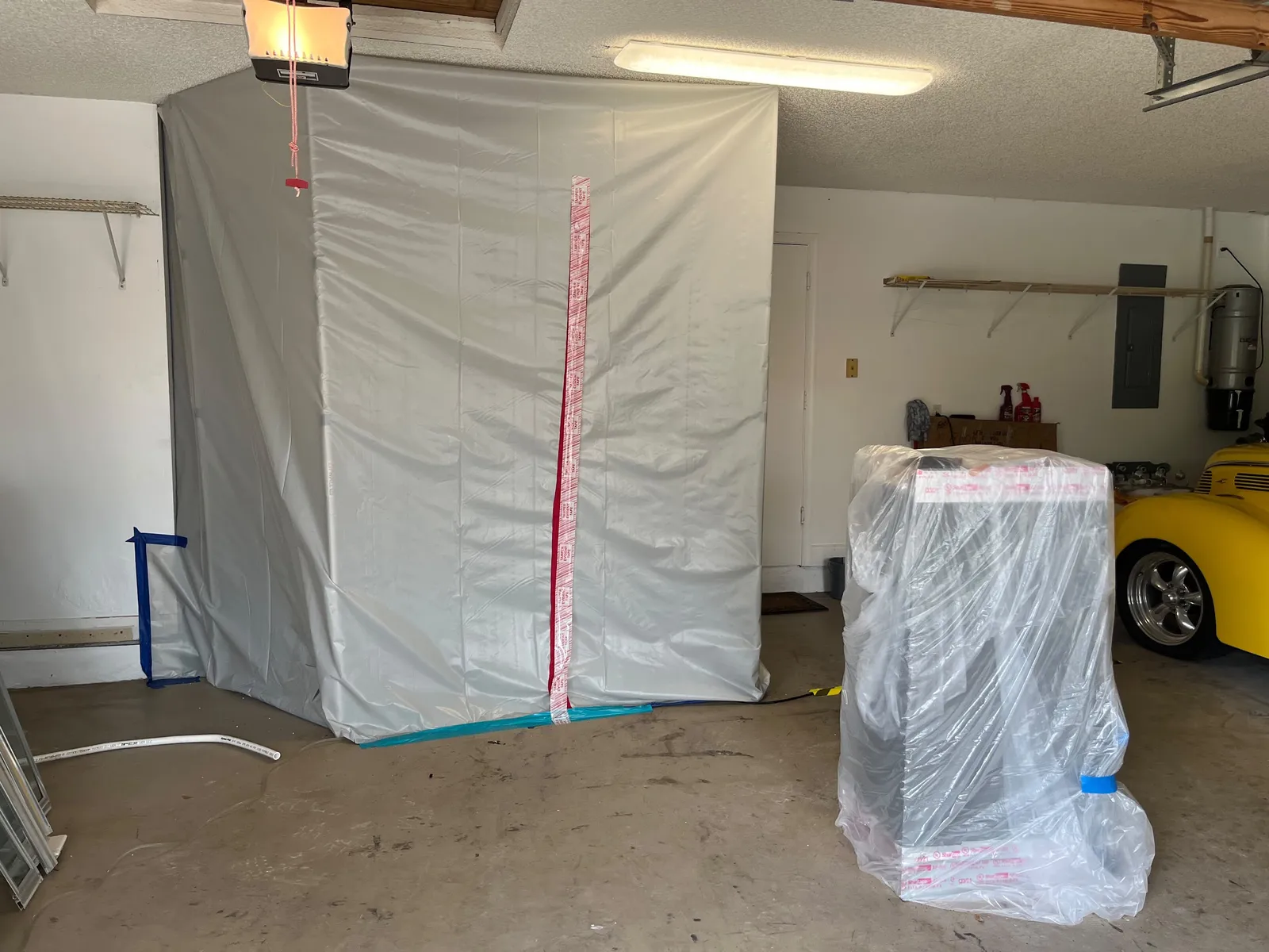A sealed plastic containment structure built inside a garage ahead of mold removal.